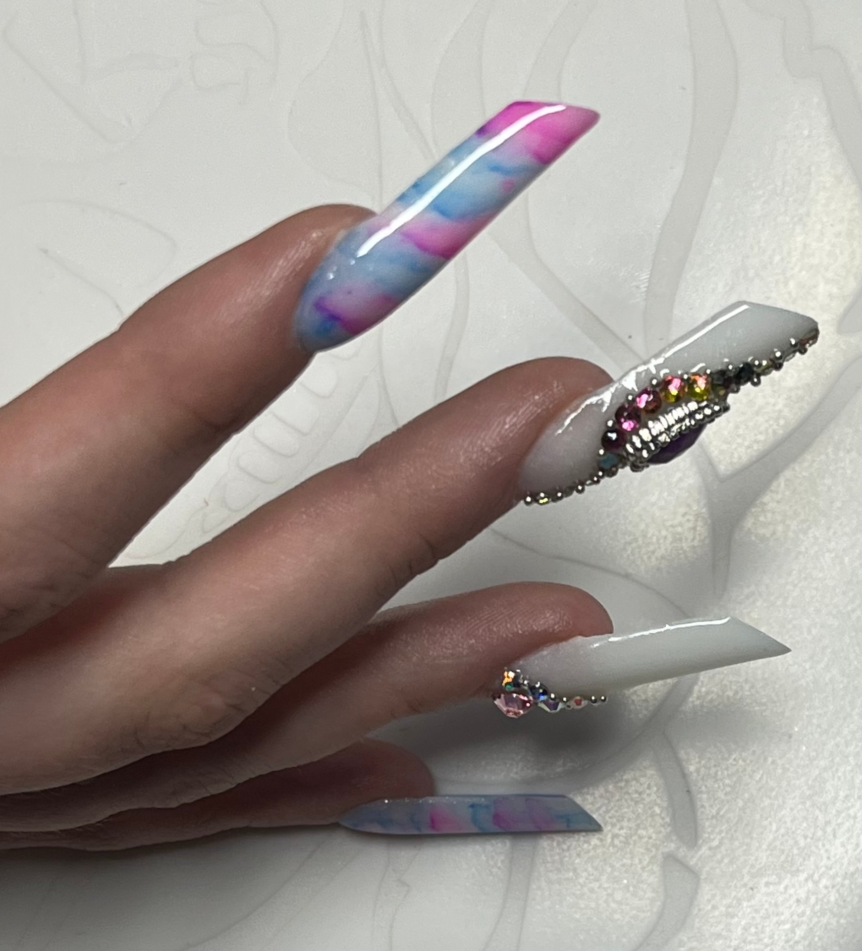 Extreme long white nails with pastel marble and encrusted gem detailing